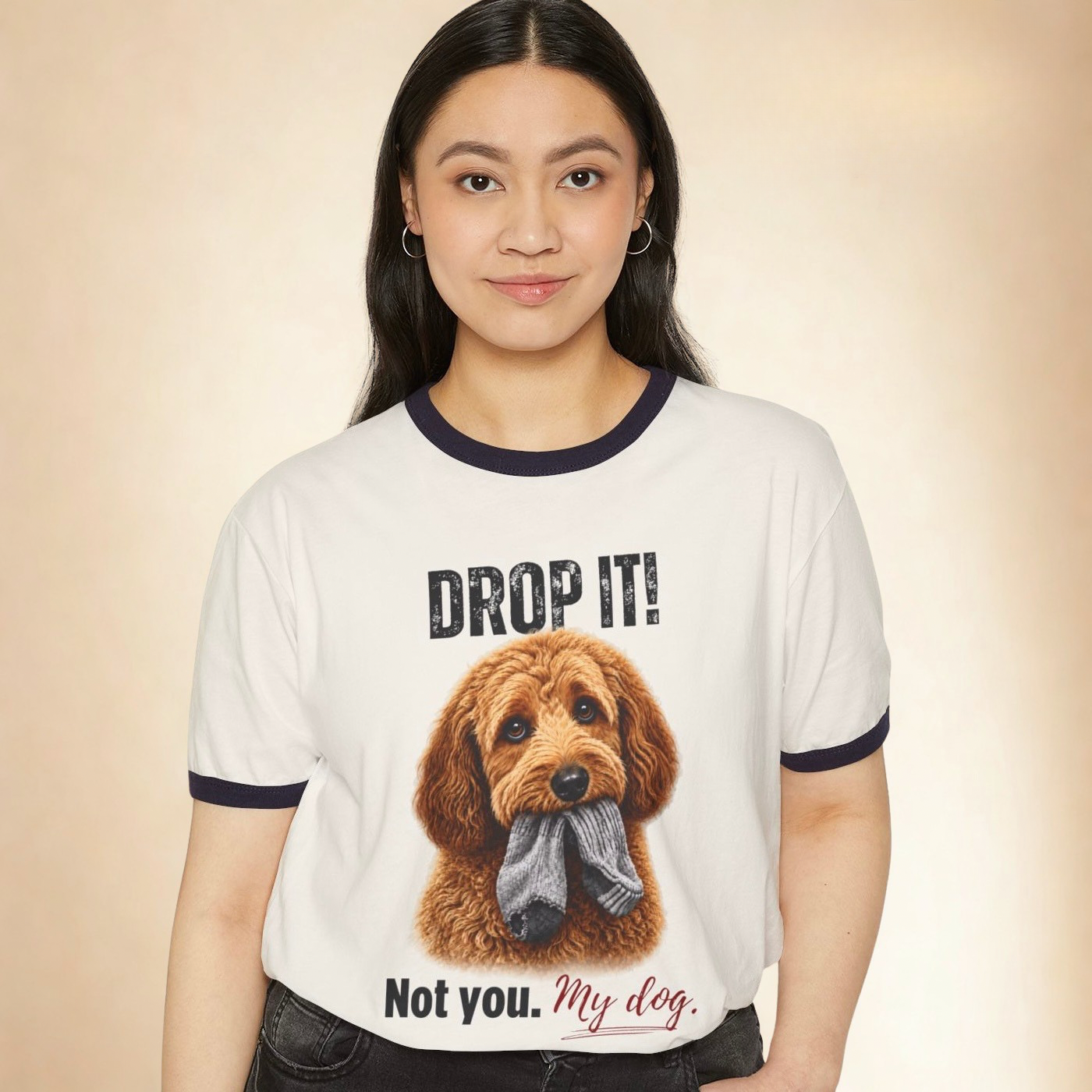 Woman wearing a white ringer T-shirt featuring a brown dog holding a sock with the text “Drop It! Not you. My dog.”