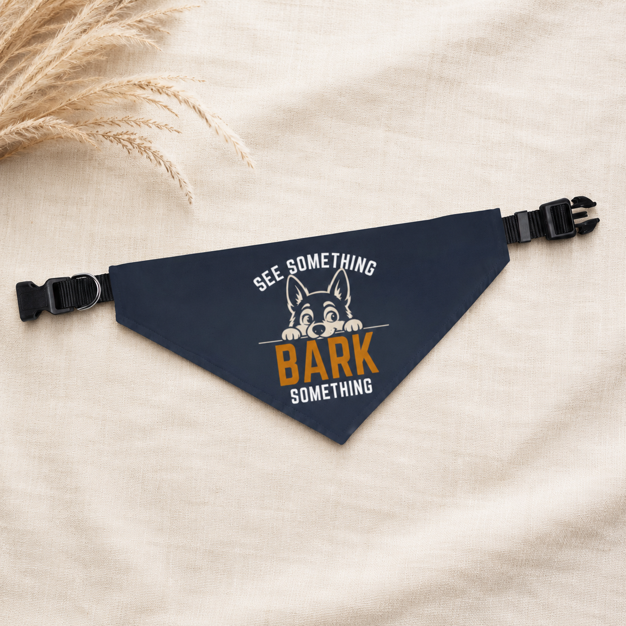Navy dog collar bandana with cartoon dog graphic styled flat on linen with dried wheat sprigs.