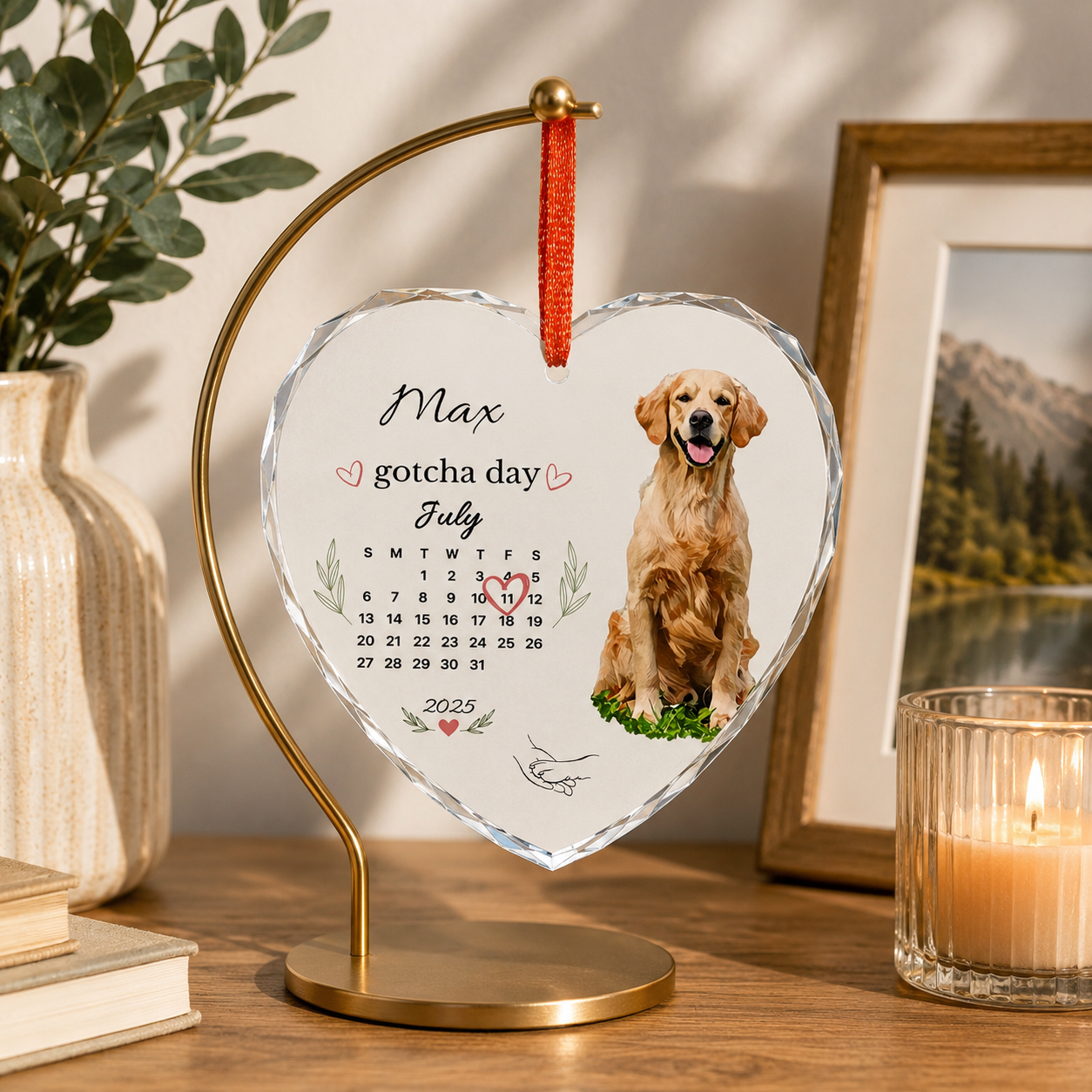 Golden retriever gotcha day ornament displayed on a gold stand beside books and a framed photo.