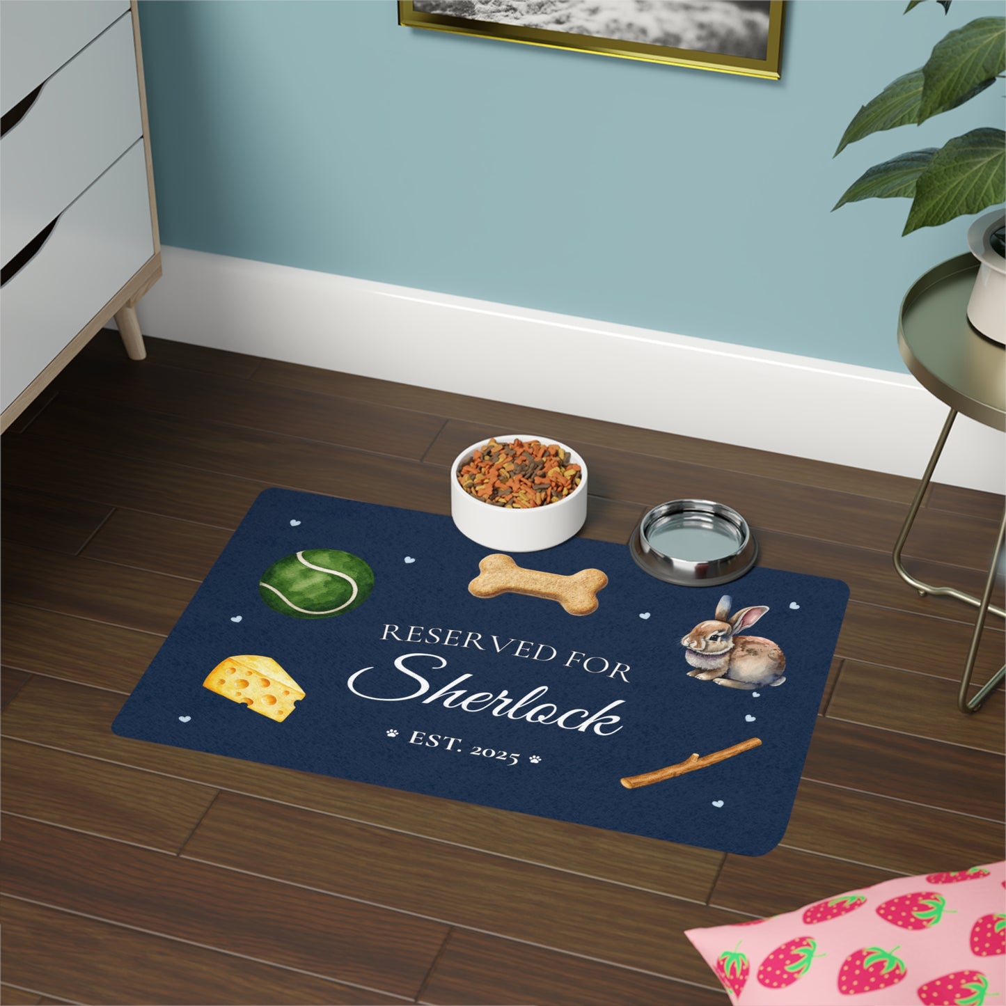Navy personalized dog feeding mat with bowls styled on a wood floor in a blue-walled room.