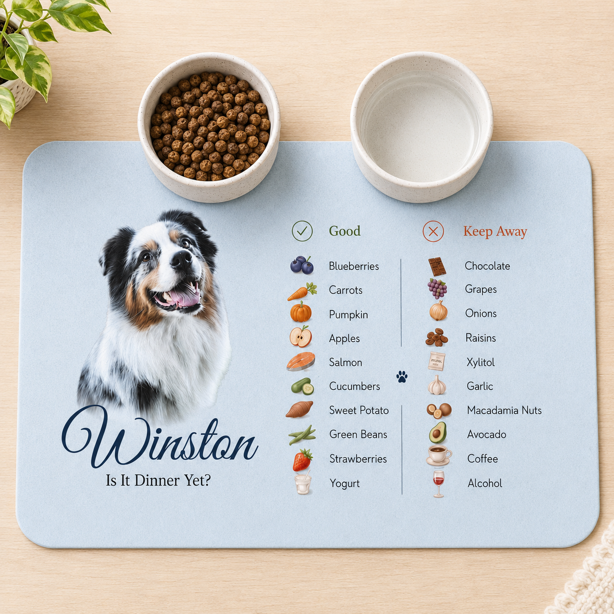 Blue personalized dog food mat with an Aussie's photo, the name Winston and a safe foods list, set with two bowls.