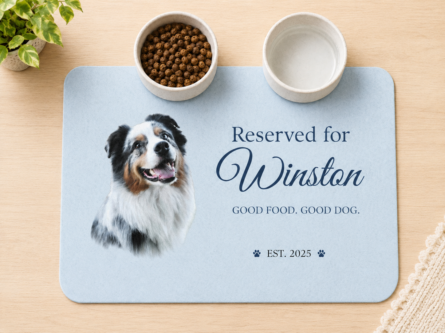Blue personalized dog placemat with an Australian Shepherd's photo and the name Winston, set with food and water bowls.